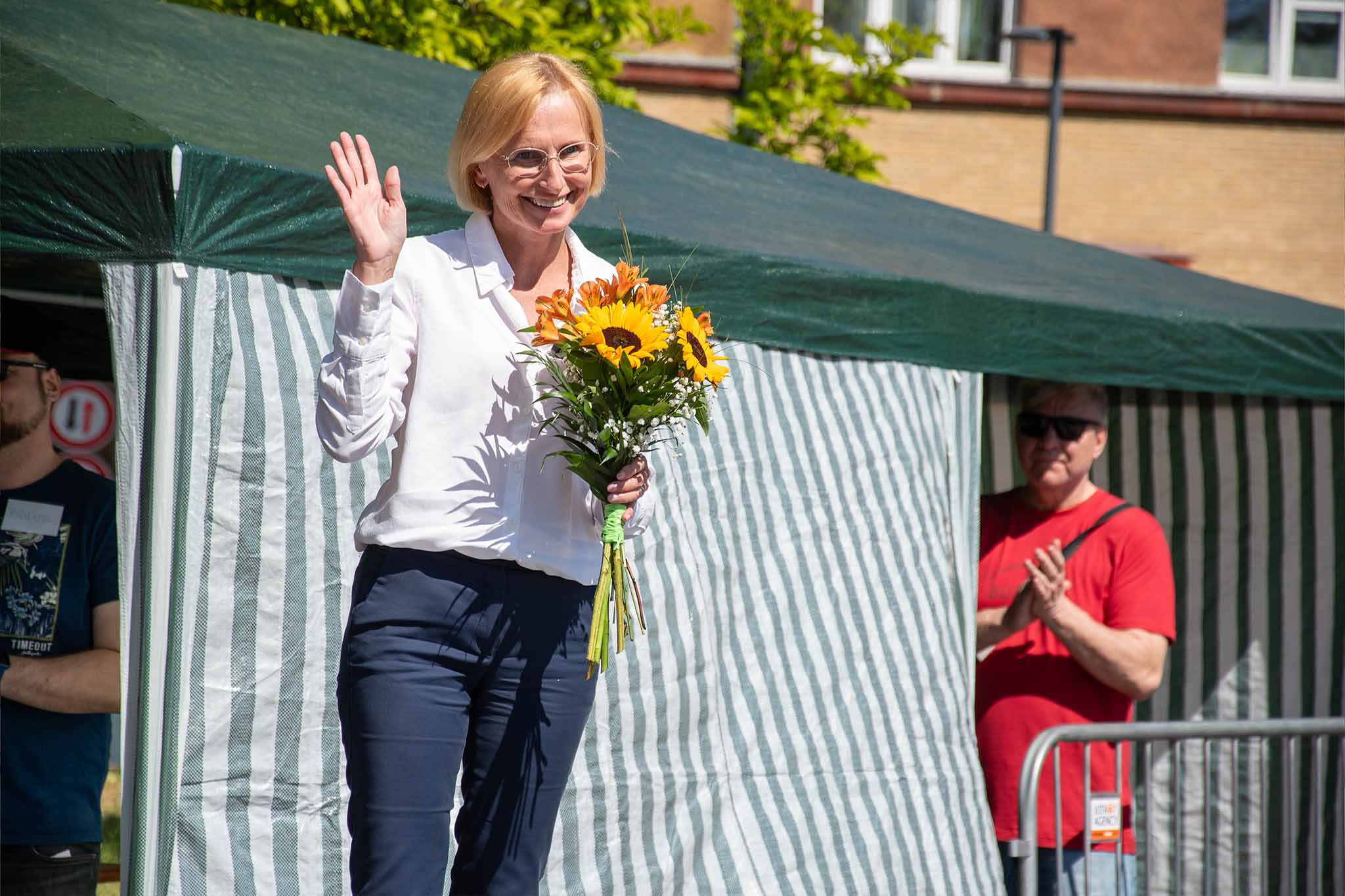 Kateřina Konečná zdraví účastníky setkání k 1. máji 2025 v Ostravě, v ruce drží kytici slunečnic
