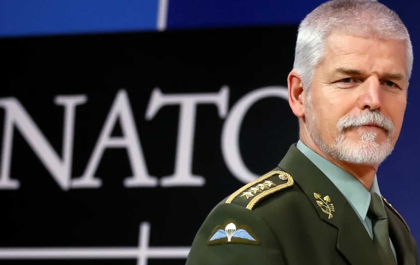 Petr Pavel  - bezpečnostní hrozba v uniformě NATO před logem Aliance – symbolické spojení loajality a politické agendy