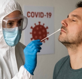 Zdravotník v ochranném obleku provádí výtěr z nosu muži během testování na COVID-19