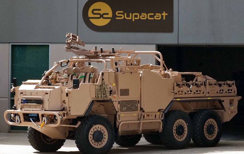 Obrněnec HMT Supacat Extenda 6×6, který chce česká armáda nakoupit třikrát dráž než britská. Foto: Supacat Obrněnec HMT Supacat Extenda 6×6 zaparkovaný před budovou s logem výrobce