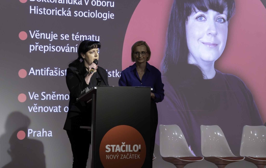 Petra Prokšanová, lídryně hnutí Stačilo! pro Prahu, během tiskové konference hnutí v Ostravě. Na pozadí promítaný profilový vizuál představující její odborné a politické zaměření. Rušení opozičních akcí – Petra Prokšanová na tiskové konferenci hnutí Stačilo! v Ostravě